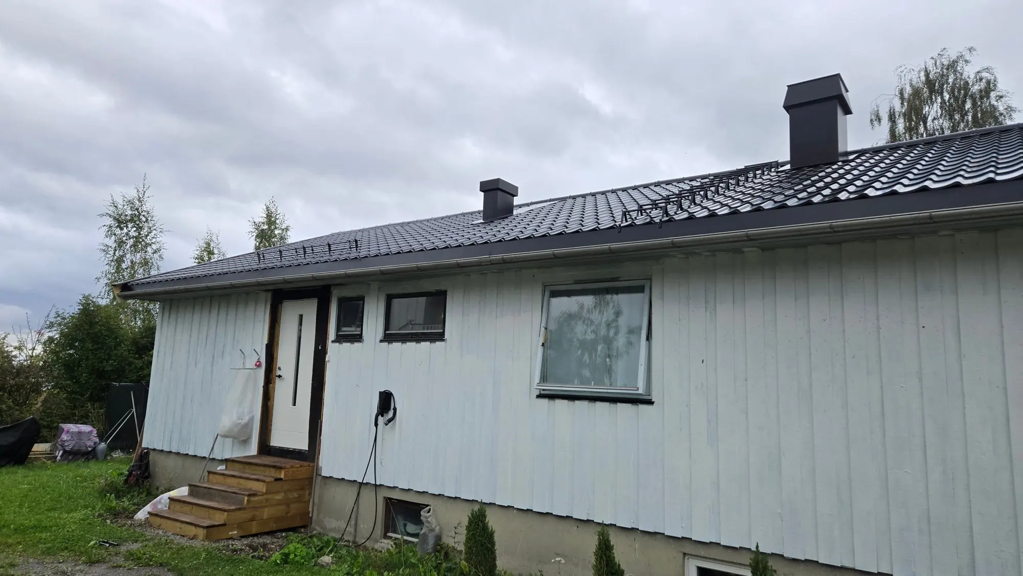 Langsiden av eneboligen med nytt tak og pipe
